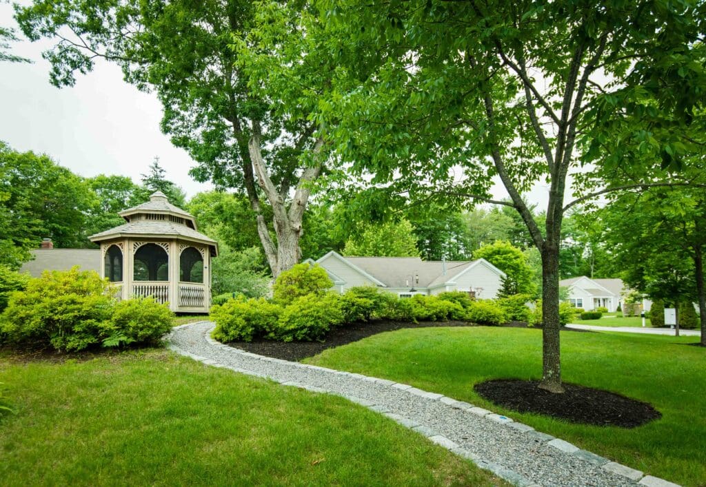 The Highlands courtyard with a gazebo, a walking path, green grass, and trees.