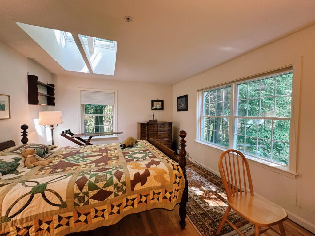 An interior bedroom with cozy furniture and beautiful natural light at The Highlands, a reliable assisted living option near Brunswick, Maine.
